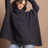 A woman wears an oversized cashmere sweater in a grey blue colour with jeans