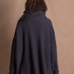 A woman wears an oversized cashmere sweater in a grey blue colour with jeans