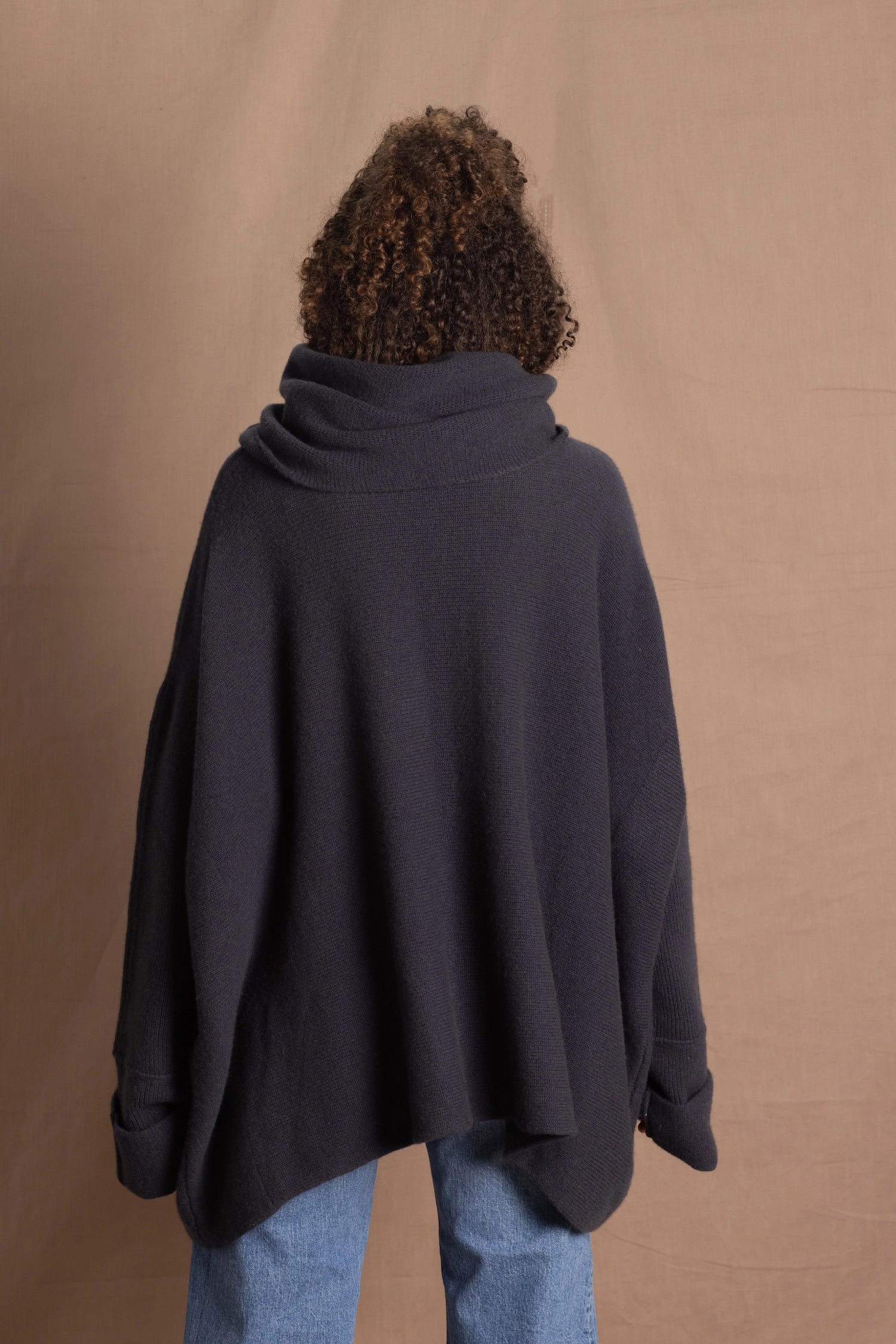 A woman wears an oversized cashmere sweater in a grey blue colour with jeans