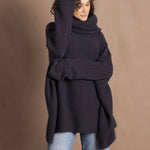 A woman wears an oversized cashmere sweater in a grey blue colour with jeans