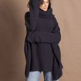 A woman wears an oversized cashmere sweater in a grey blue colour with jeans
