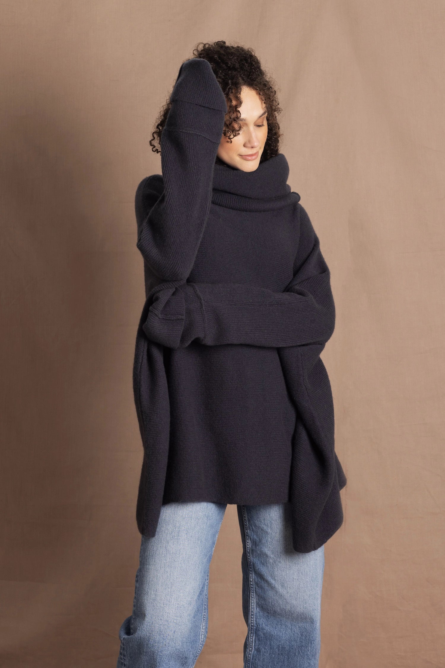 A woman wears an oversized cashmere sweater in a grey blue colour with jeans