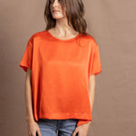 A woman wears an oversized 100% silk t-shirt in orange