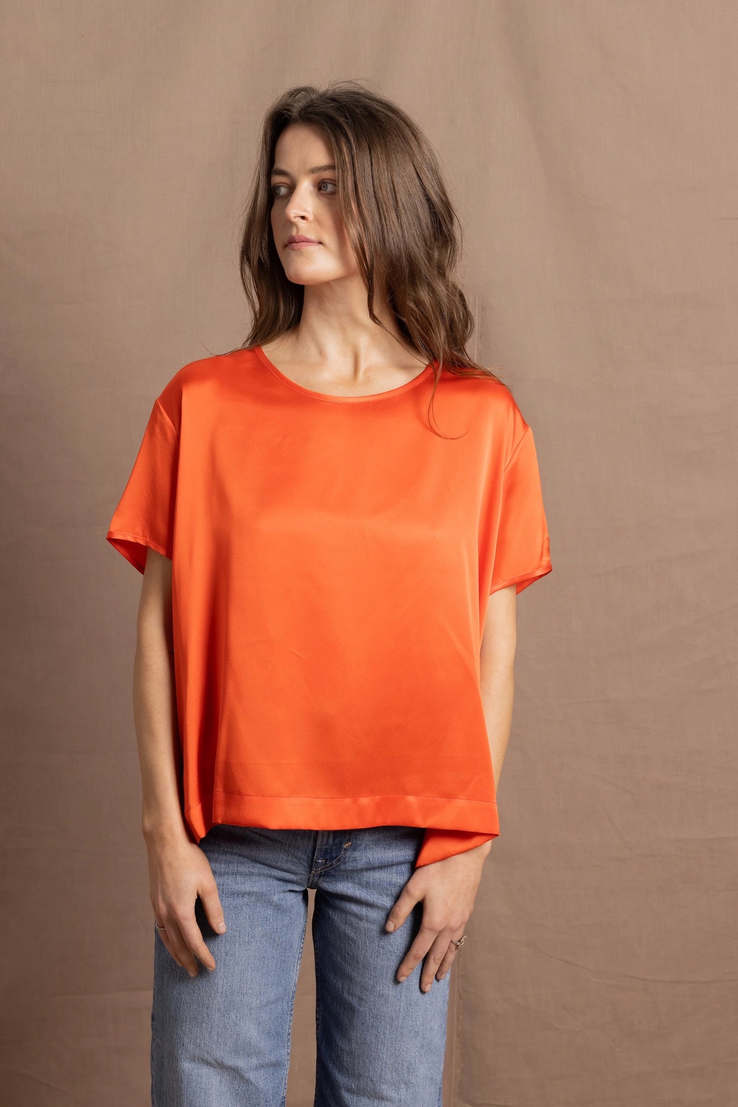 A woman wears an oversized 100% silk t-shirt in orange