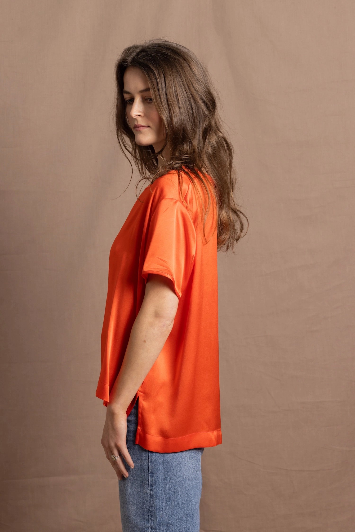 A woman wears an oversized 100% silk t-shirt in orange