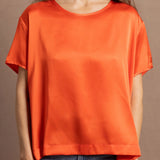 A woman wears an oversized 100% silk t-shirt in orange