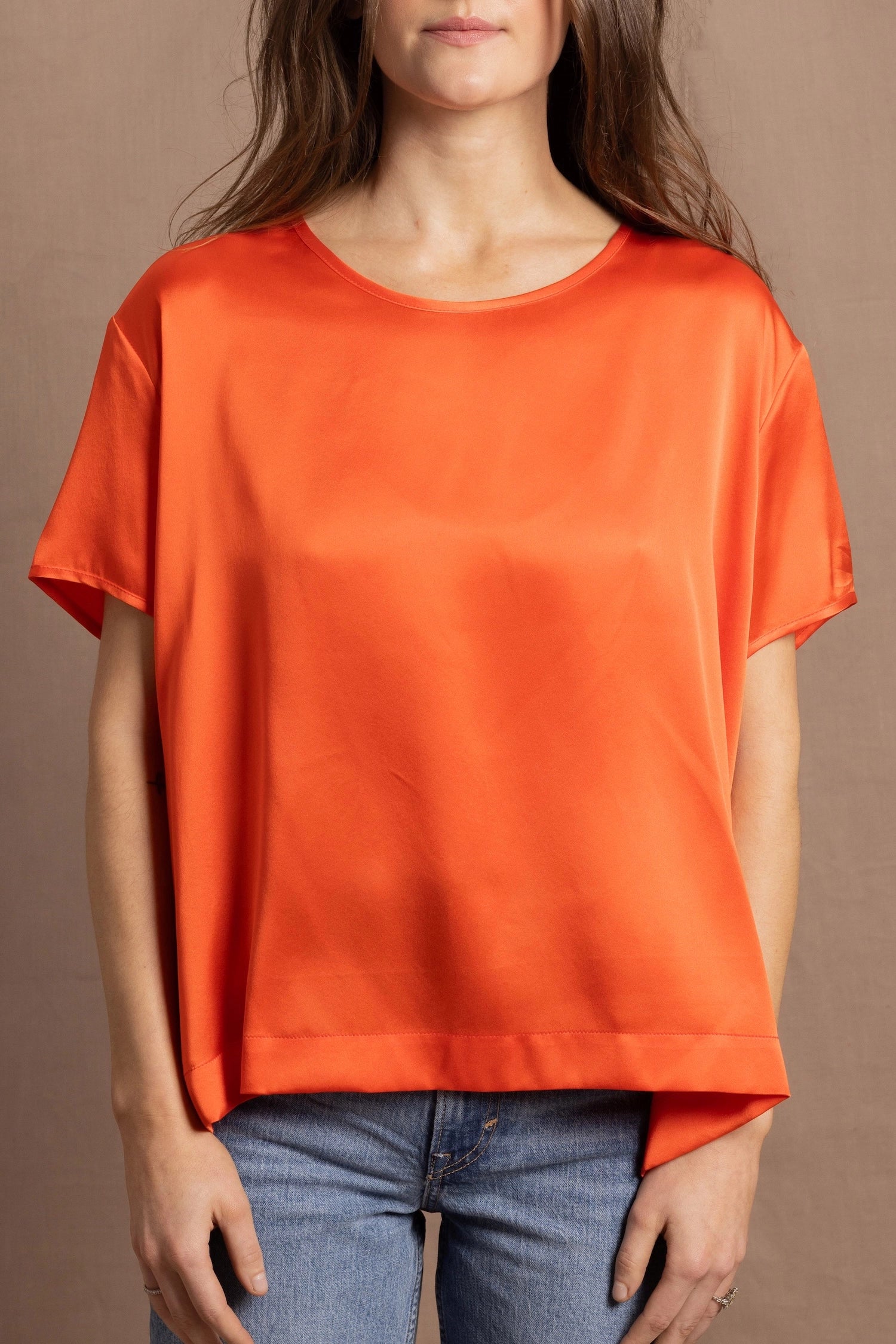 A woman wears an oversized 100% silk t-shirt in orange
