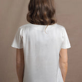 A woman wears a 100% silk v-neck t-shirt in white with a pair of jeans