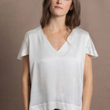 A woman wears a 100% silk v-neck t-shirt in white with a pair of jeans