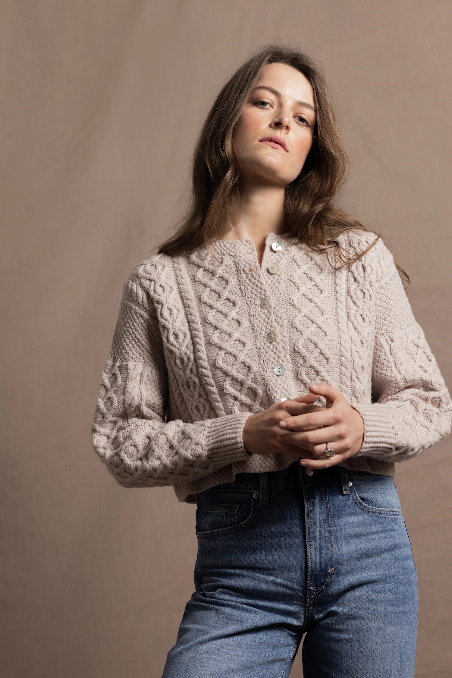 A lady wears a pure 100% cashmere Irish aran sweater cardigan in soft pink 