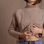 a woman wears a taupe coloured cashmere aran turtleneck sweater