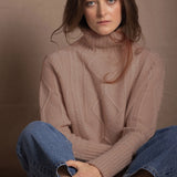 a woman wears a taupe coloured cashmere aran turtleneck sweater