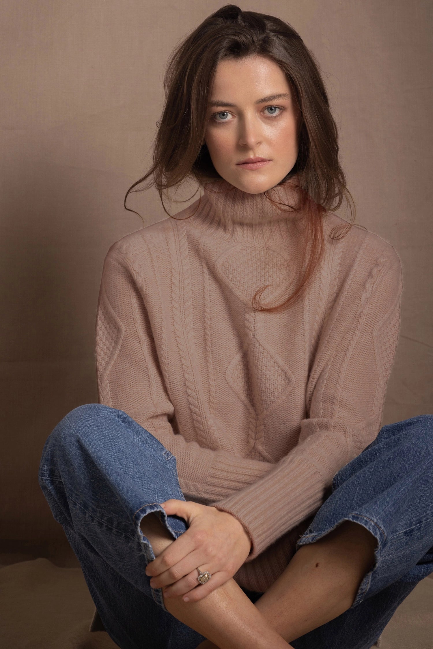 a woman wears a taupe coloured cashmere aran turtleneck sweater