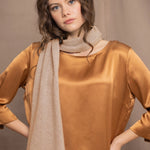 a woman wears a cashmere scarf in sand beige colour over bronze silk top