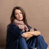 A woman wears a small 100% cashmere scarf in blush pink over a teal 100% silk top and matching trousers