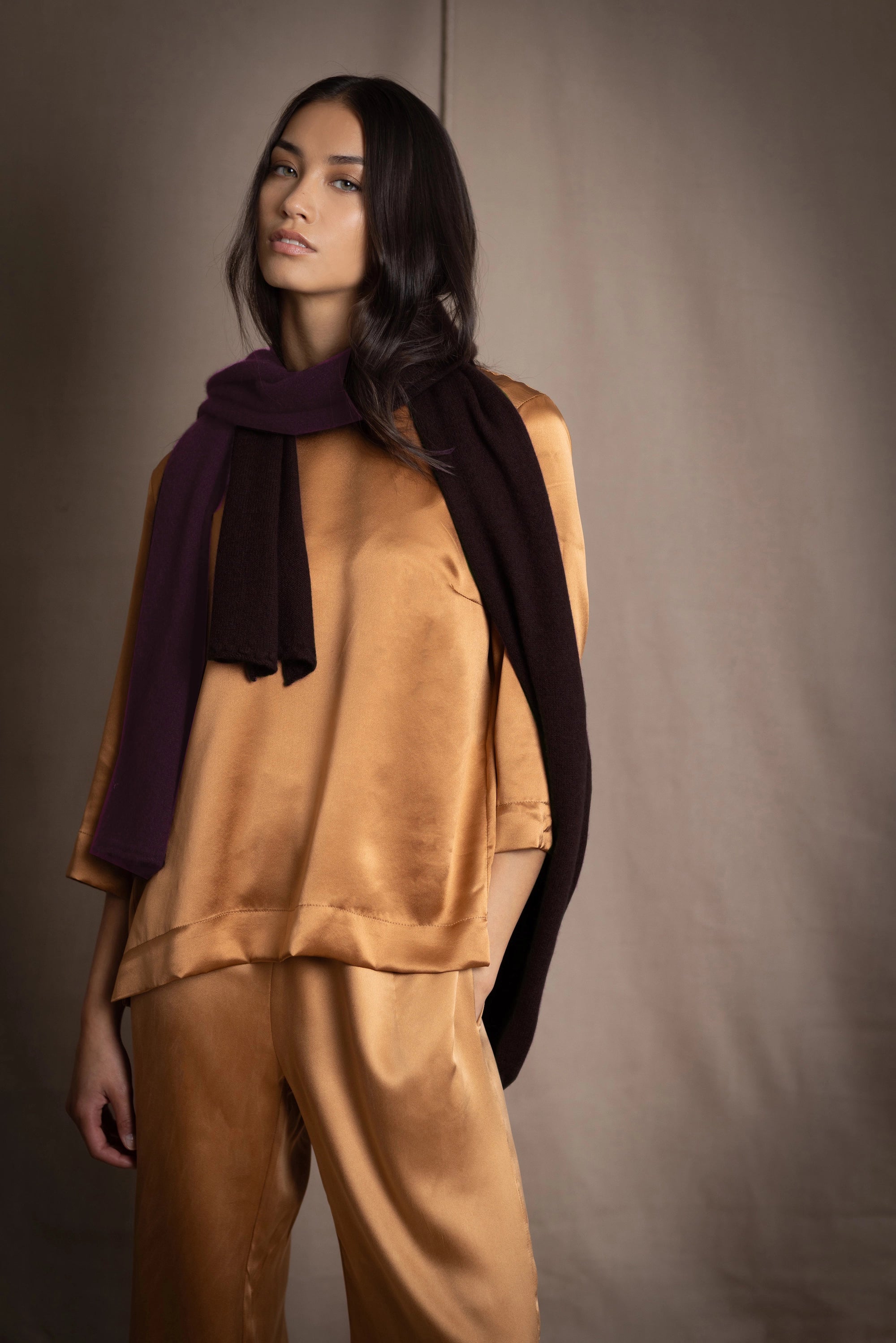 a woman wearing a cashmere scarf in dark brown over bronze silk clothing 