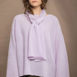 a woman wears a small pale light purple cashmere scarf over a matching cashmere sweater from Irish brand Madigan