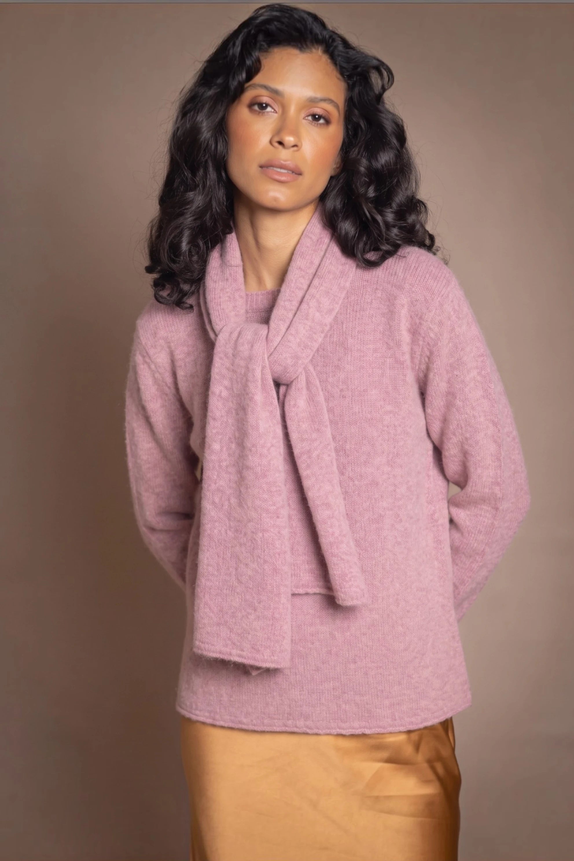 A woman modelling a dusty pink cashmere scarf with a matching cashmere turtleneck sweater jumper by Irish Luxury brand Madigan Cashmere