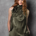Woman wearing an olive green sleeveless silk top with a bow 