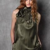 Woman wearing an olive green sleeveless silk top with a bow 