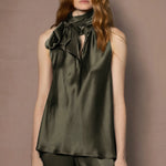 Woman wearing an olive green sleeveless silk top with a bow 