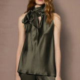 Woman wearing an olive green sleeveless silk top with a bow 