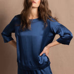 A lady wears a pure silk 3/4 sleeve blouse in teal with matching trousers