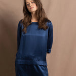 A lady wears a pure silk 3/4 sleeve blouse in teal with matching trousers