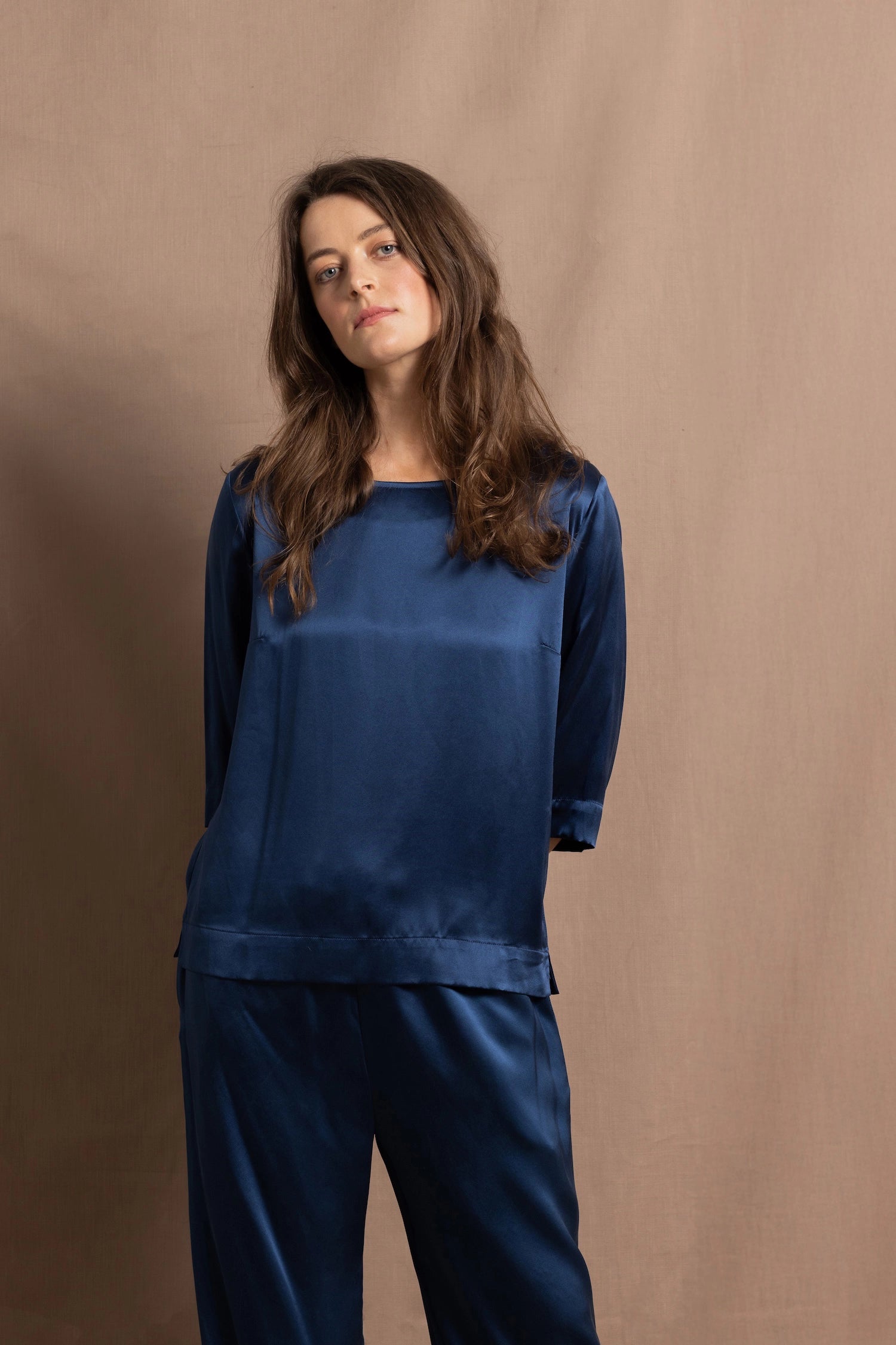 A lady wears a pure silk 3/4 sleeve blouse in teal with matching trousers