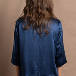 A lady wears a pure silk 3/4 sleeve blouse in teal with matching trousers