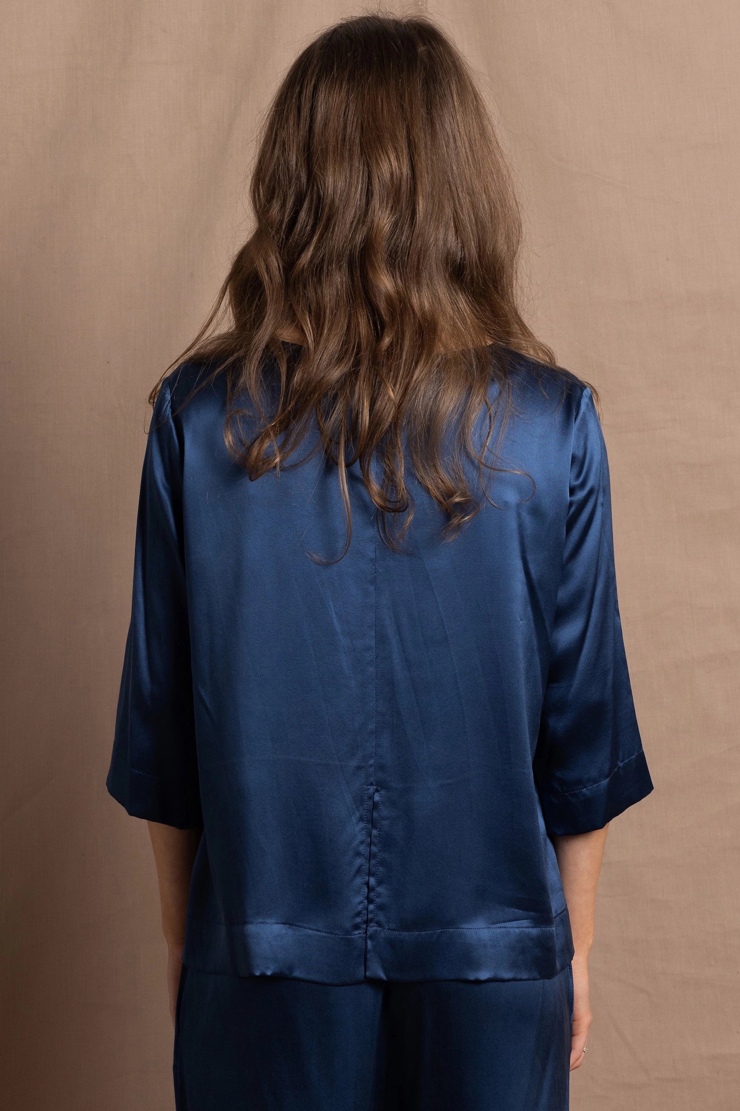 A lady wears a pure silk 3/4 sleeve blouse in teal with matching trousers