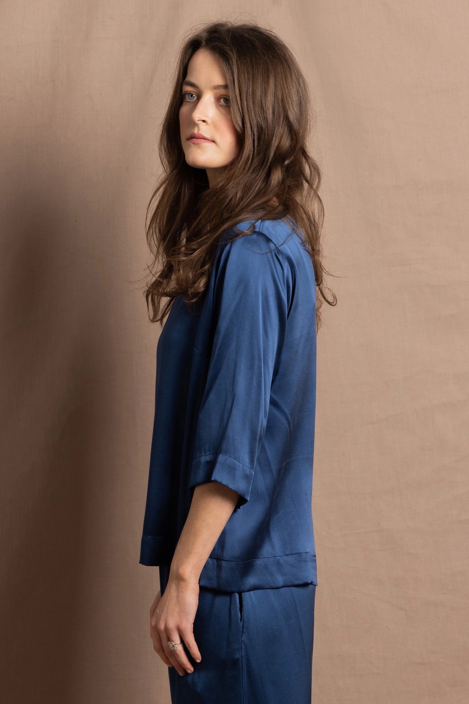 A lady wears a pure silk 3/4 sleeve blouse in teal with matching trousers