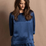 A lady wears a pure silk 3/4 sleeve blouse in teal with matching trousers