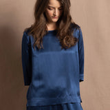 A lady wears a pure silk 3/4 sleeve blouse in teal with matching trousers