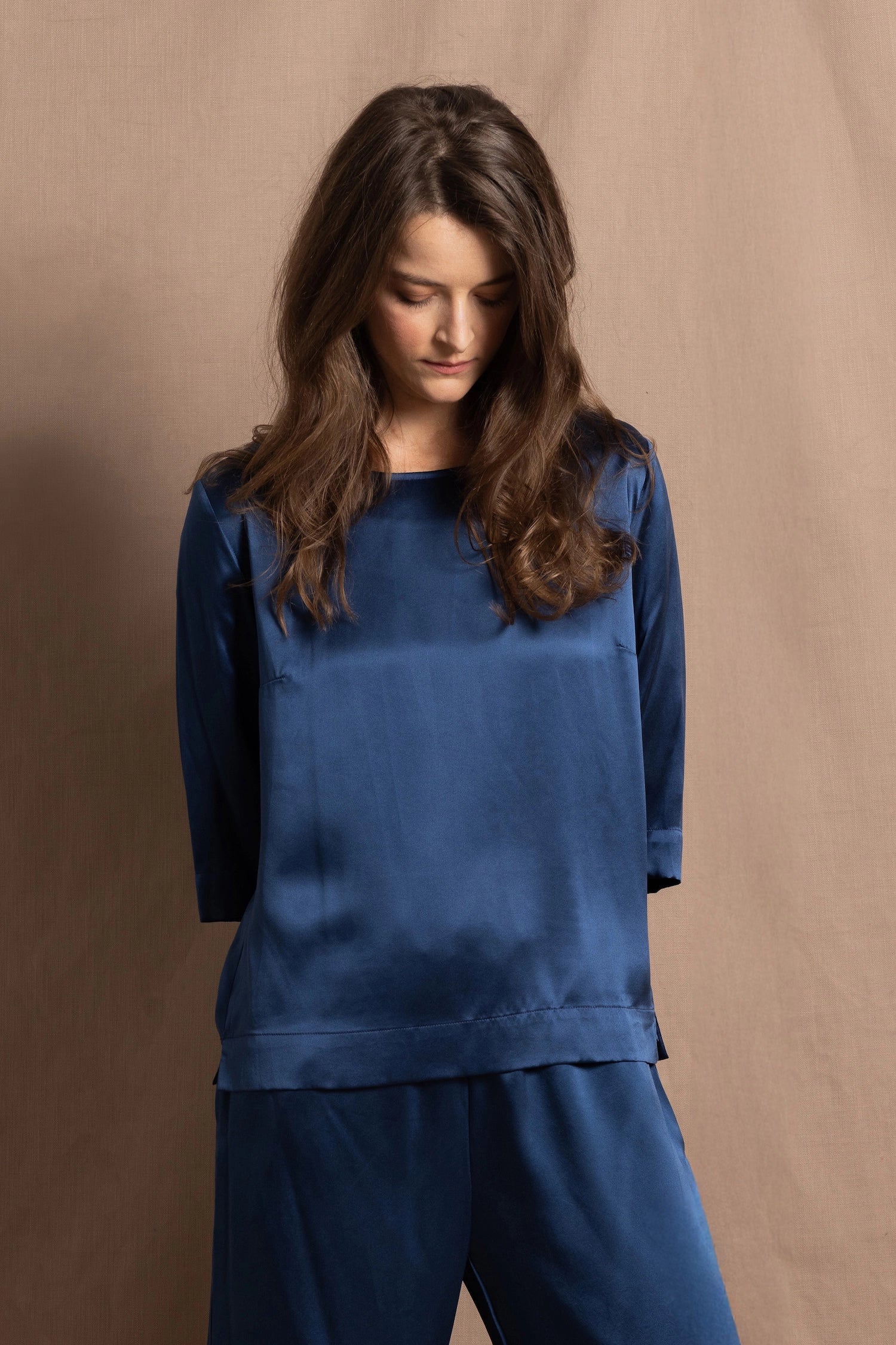 A lady wears a pure silk 3/4 sleeve blouse in teal with matching trousers