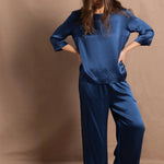 A lady wears a pure silk 3/4 sleeve blouse in teal with matching trousers