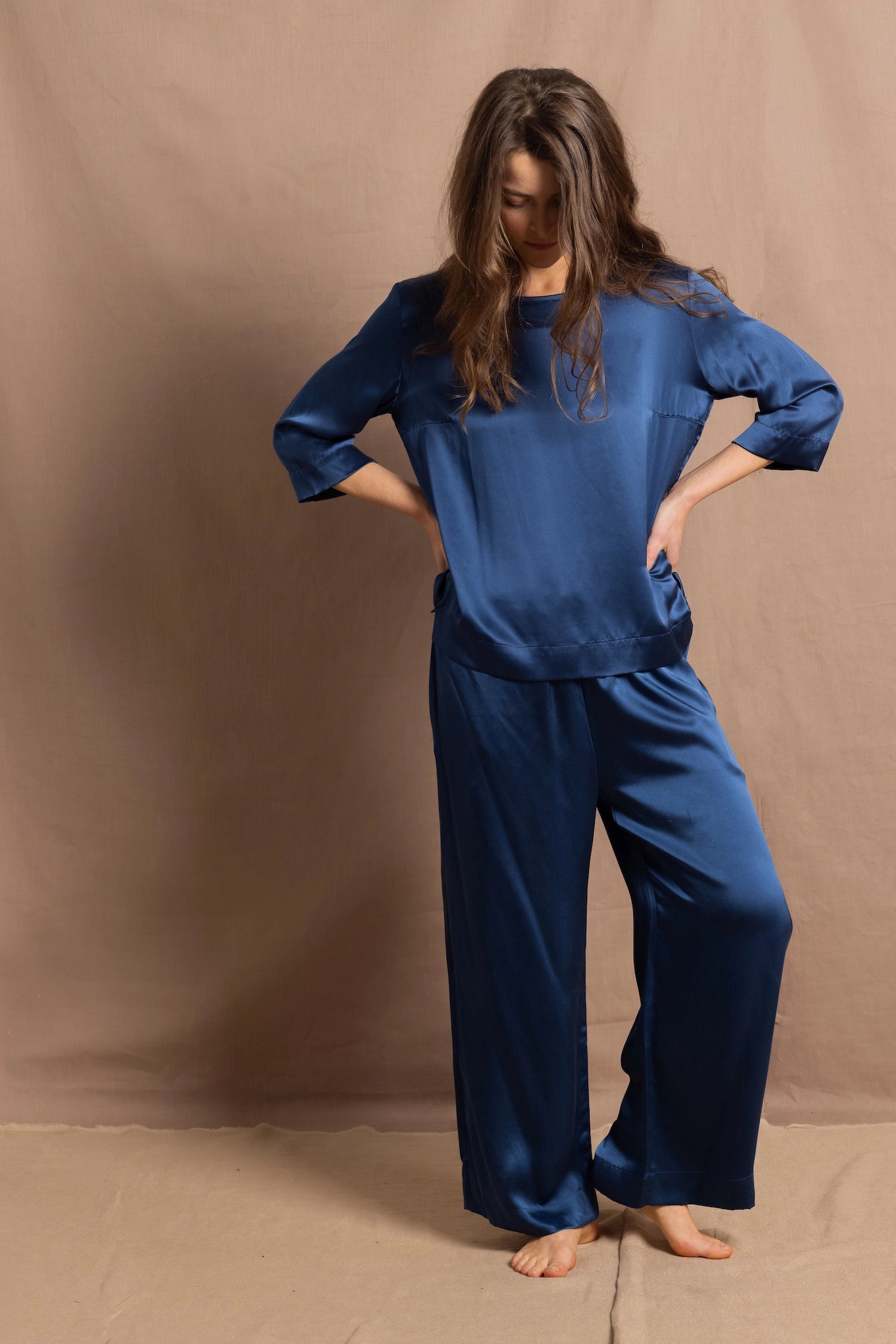 A lady wears a pure silk 3/4 sleeve blouse in teal with matching trousers