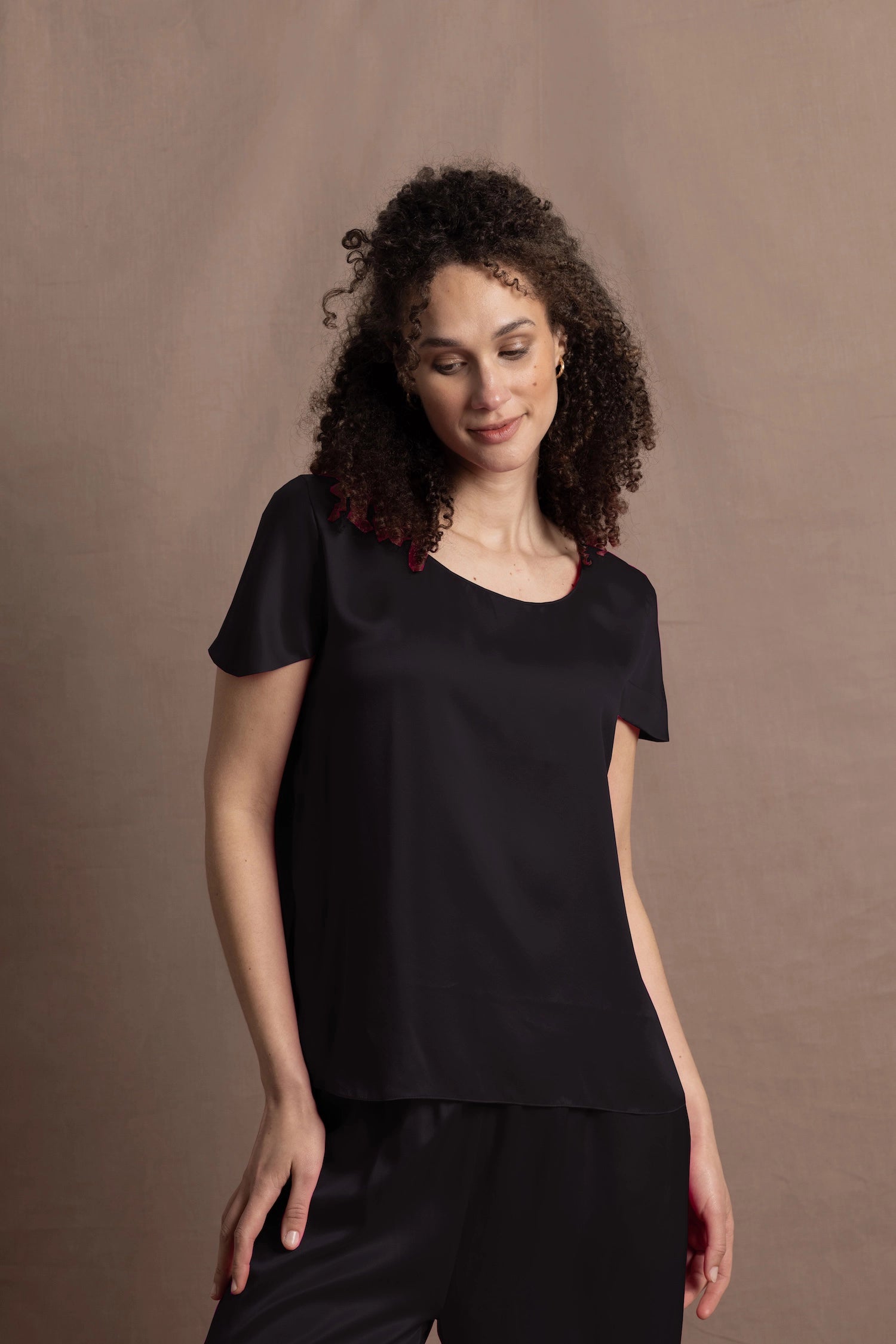 a woman wears a black crew neck short sleeve silk tee and matching trousers