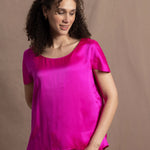 A woman wears a pure 100% silk t-shirt in bright pink with matching trousers