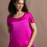 A woman wears a pure 100% silk t-shirt in bright pink with matching trousers