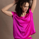 A woman wears a pure 100% silk t-shirt in bright pink with matching trousers