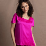 A woman wears a pure 100% silk t-shirt in bright pink with matching trousers