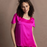 A woman wears a pure 100% silk t-shirt in bright pink with matching trousers