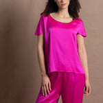 A woman wears a pure 100% silk t-shirt in bright pink with matching trousers