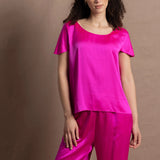 A woman wears a pure 100% silk t-shirt in bright pink with matching trousers