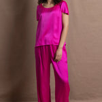A woman wears a pure 100% silk t-shirt in bright pink with matching trousers