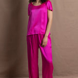 A woman wears a pure 100% silk t-shirt in bright pink with matching trousers