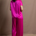 A woman wears a pure 100% silk t-shirt in bright pink with matching trousers