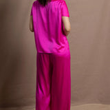 A woman wears a pure 100% silk t-shirt in bright pink with matching trousers