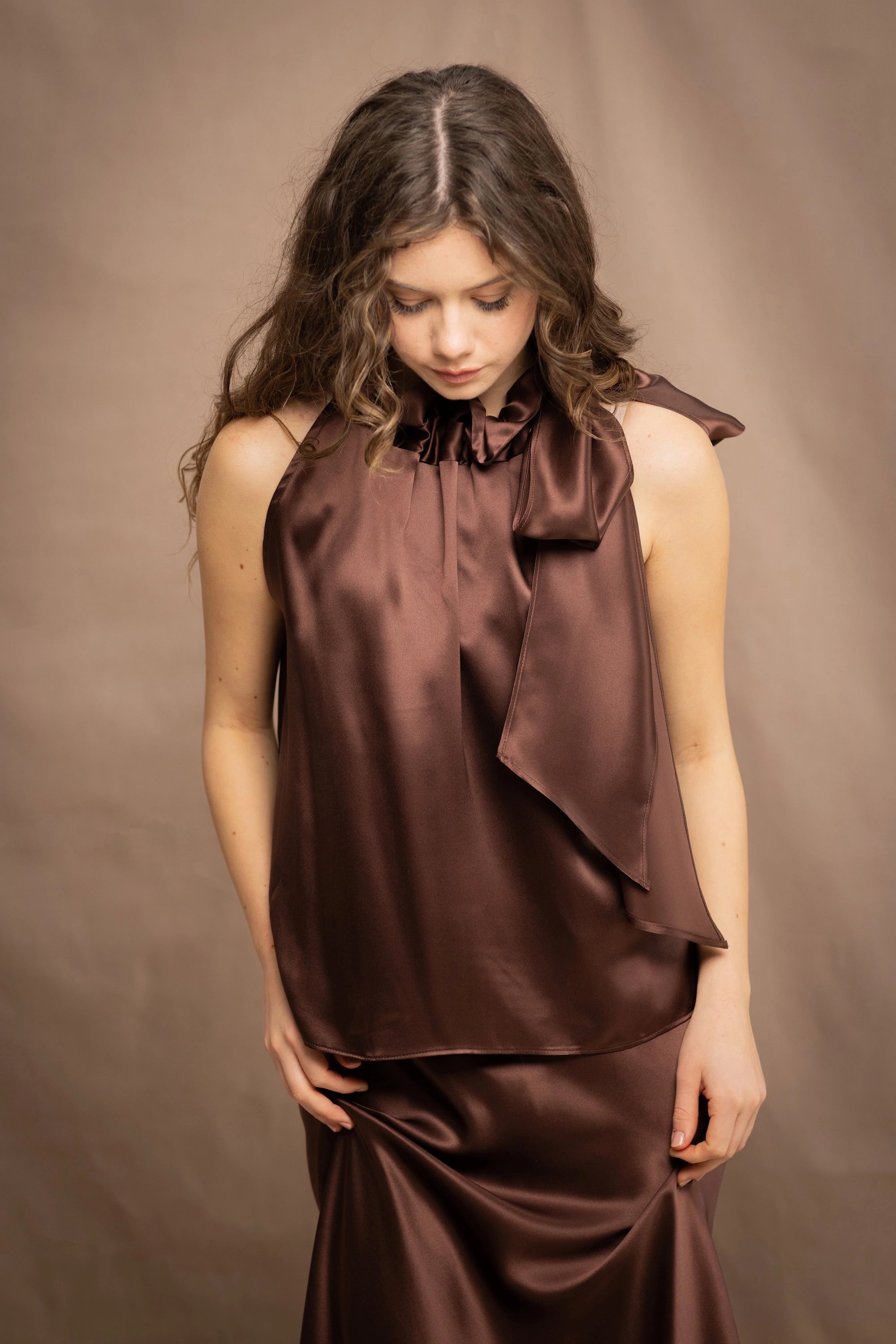 a woman wears a pure 100% silk halter top in chocolate brown with matching silk skirt